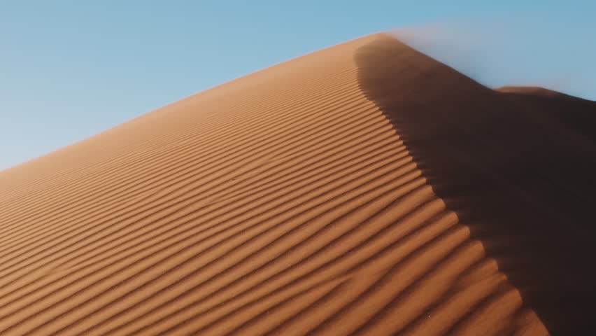 Sand dune ridge with wind ripples, wind blows sand from the peak dune in sossusvlei, namibia.