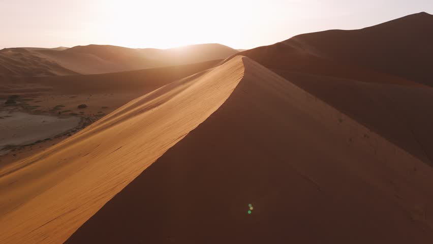 Aerial view of sand dune in the sossusvlei desert in namibia, with the golden sunrise.