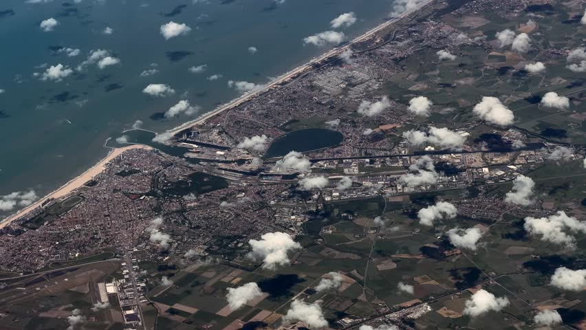 flying across the North Sea coastline with long white sandy beaches near City of Ostend, Belgium, with Harbor, cityscape, streets and buildings, located at Spuikom, a large, artificial tidal reservoir - 4k aerial video footage 
