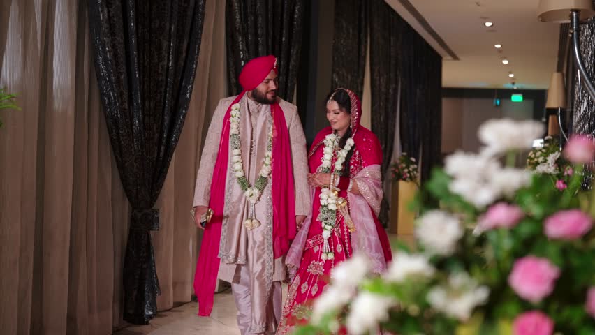 Romantic Punjabi Newlyweds Holding Hands After Varmala Ceremony In Elegant Hallway
