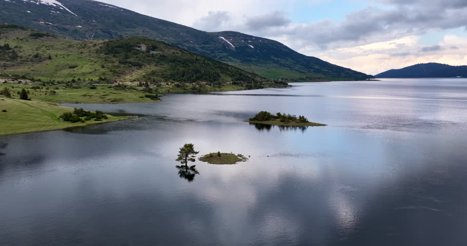 Two small island in a high mountain dam in a cloudy day, drone view