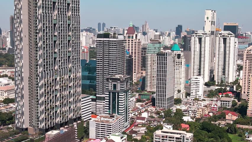 In the heart of Bangkok, tall buildings rise above the city. Streets are filled with activity, reflecting the vibrant urban life and the mix of modern and traditional architecture.