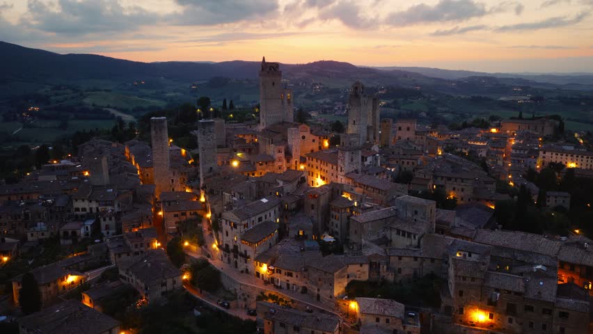 night drone view of San Gimignano with night city lights, medieval village in Tuscany aerial view in the evening, travel in Italy, Italian historic town of San Gimignano