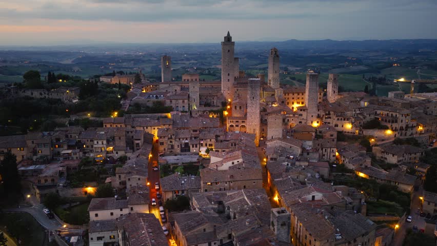 Orbiting drone shot of San Gimignano with night illumination in the evening, travel in Tuscany, Italy, Tuscan medieval village of San Gimignano at night