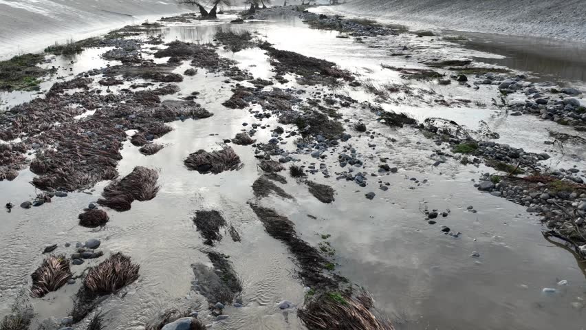 Aerial shot of flood damage and trash in the Los Angeles River after heavy rains.