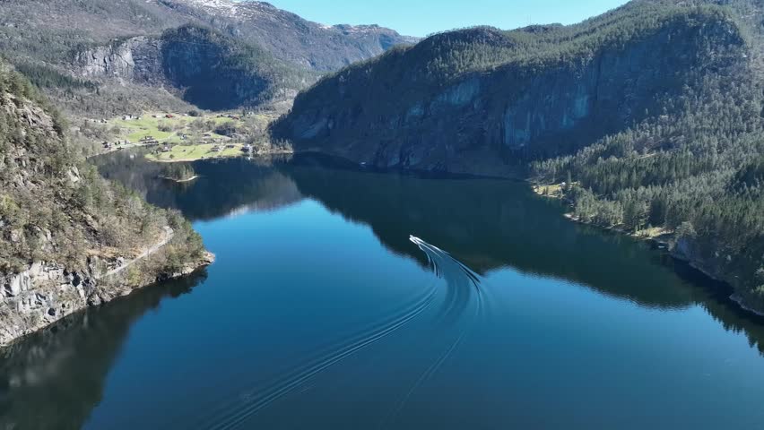 Boat cruising on calm fjord water near Stamnes Vaksdal Norway with mountain reflections