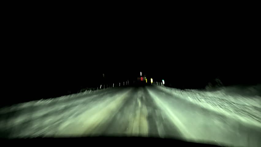 A fast-moving car on a snowy night drive in the country.