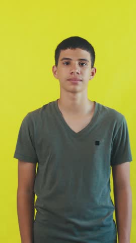 Happy young man with a bright smile waving his hands in a friendly greeting. Joyful male portrait on a vibrant yellow studio background