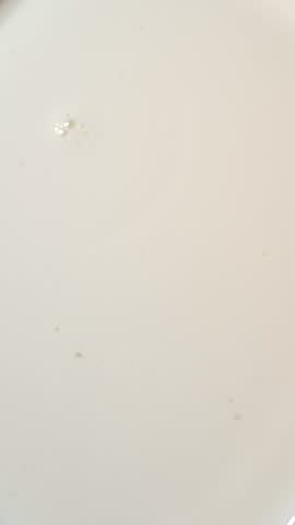 Close-up view of a fresh ripe strawberry falling into thick white milk or yogurt with a soft splash.