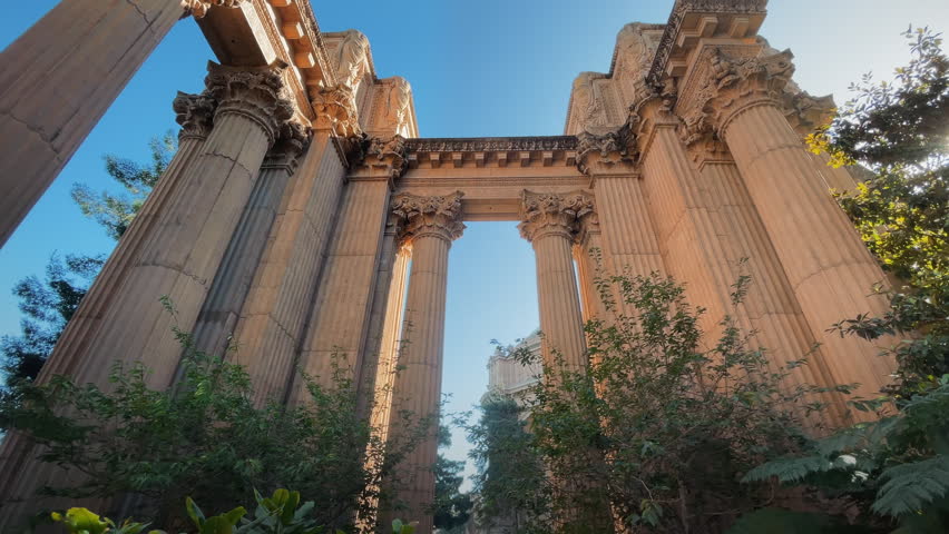 Handheld 4K footage captures a smooth tilt-down movement from the ornate crown of the neoclassical columns down to ground level at the Palace of Fine Arts in San Francisco, California. The movement reveals the full monumental scale of the structure, originally built for the 1915 Panama-Pacific International Exposition and designed by architect Bernard Maybeck in a Roman and Greek classical style. The Palace of Fine Arts is one of San Francisco most beloved and photographed landmarks, set alongside a scenic lagoon in the Marina District. The tilt-down technique emphasizes vertical grandeur and architectural detail, evoking themes of history, human achievement and timeless artistic elegance. Ideal for architecture, travel, art and cultural heritage commercial campaigns