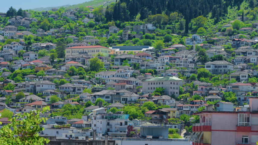 Mountain town hillside houses urban slope scenery, handheld shot. Panoramic view of residential buildings climbing up alpine village ridge incline.