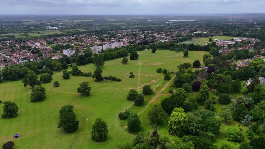 Aerial wide shot of Prospect Park, Reading, green trees and city buildings under overcast sky