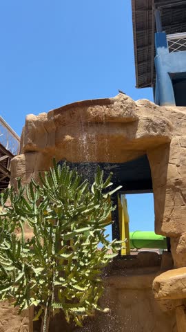 Artificial waterfall with stone arch and cactus in a water park