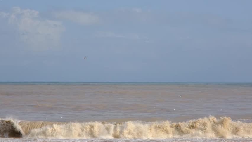 Large Muddy Waves Crashing onto Shore After Storm. Stormy Sea with Powerful Waves Hitting the Coast. Rough Brown Sea and Strong Coastal Wave Action.
