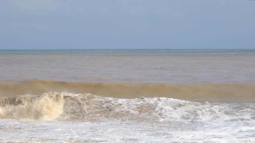 Large Muddy Waves Crashing onto Shore After Storm. Stormy Sea with Powerful Waves Hitting the Coast. Rough Brown Sea and Strong Coastal Wave Action.