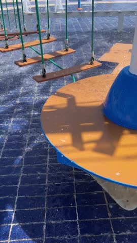 Suspended wooden plank path over a blue tiled water fountain in a park