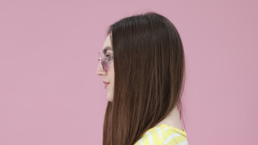 Young woman wearing stylish sunglasses on pink background