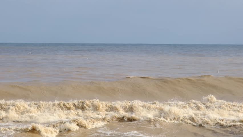 Large Muddy Waves Crashing onto Shore After Storm. Stormy Sea with Powerful Waves Hitting the Coast. Rough Brown Sea and Strong Coastal Wave Action.