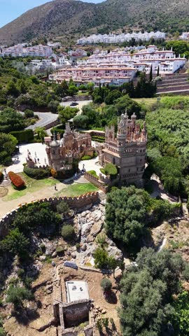 Vertical drone aerial establishing shot of Colomares Castle in Benalmádena, Málaga, Spain, revealing the unique monument dedicated to Christopher Columbus surrounded by gardens