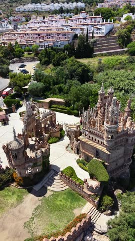 Vertical drone aerial view of Colomares Castle in Benalmádena, Málaga, Spain, showcasing its ornate towers, decorative architecture and unique monument dedicated to Christopher Columbus