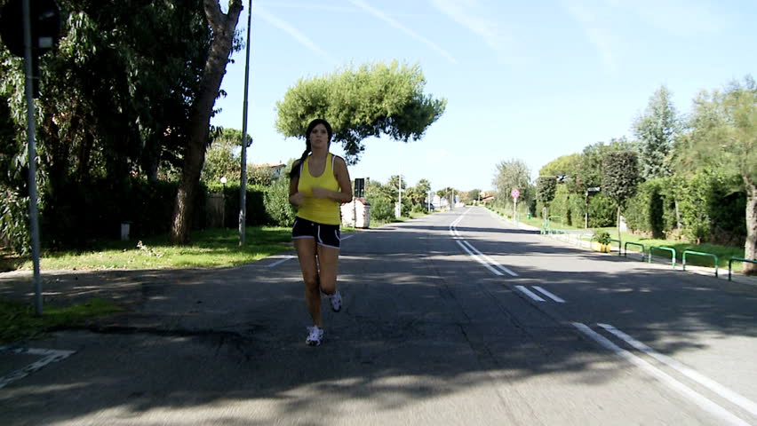 Gorgeous female athlete running on street exercizing dolly shot