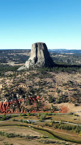 Aerial drone view of Devils Tower National Monument rising dramatically above the surrounding landscape in Wyoming, US. Vertical