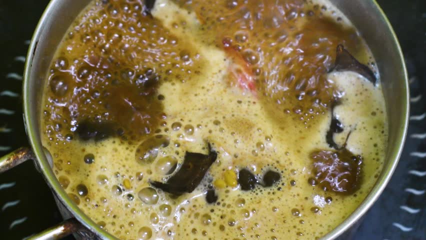 Traditional Ayurvedic shampoo preparation process featuring reetha, shikakai and jojoba flowers simmering in water on an induction cooktop for natural hair care.