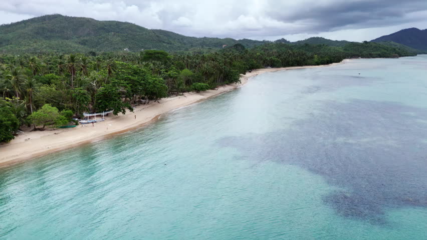 Push-in drone shot over Dipnay Beach during calm but cloudy weather, highlighting peaceful coastal scenery.