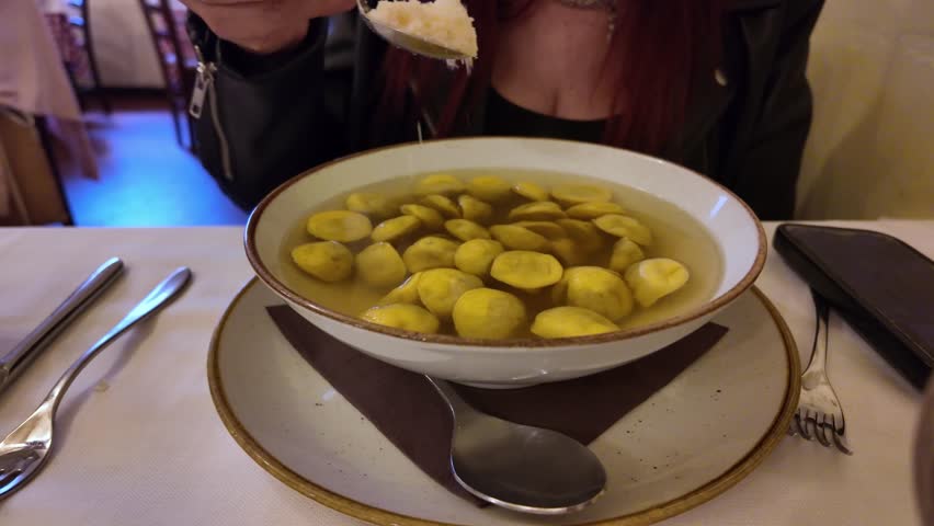 Traditional tortelli in brodo served in a restaurant in Parma, Italy. Authentic Italian comfort food featuring handmade stuffed pasta in rich broth, topped with grated Parmigiano Reggiano cheese.