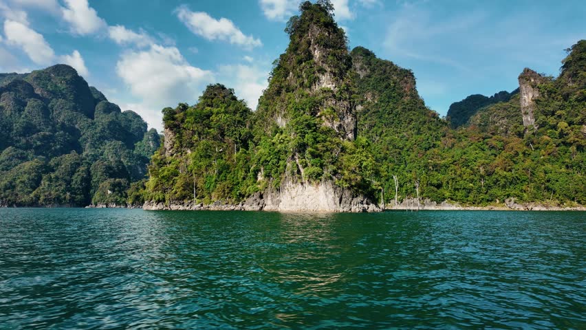 Khao sok national park lake view from boat in Thailand. Tracking shot of wooden boat bow gliding across mountain lake.