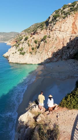 A couple of men and women at Kaputas Beach, Kas, Turkey, as visitors enjoy the serene beaches and cliffs. Turquoise waters and golden sands create a perfect backdrop for relaxation and adventure.