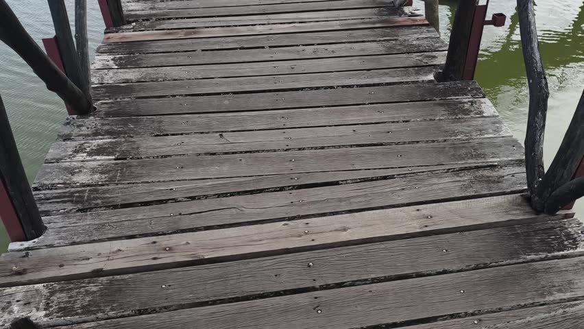 A wooden boardwalk bridge curving across a lake