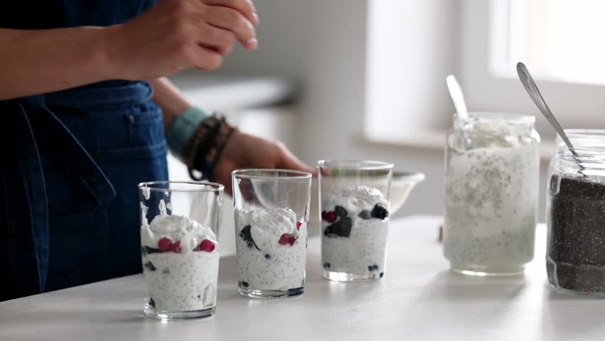 Female Hands Add Fresh Red And Black Berries To Homemade Yogurt With Chia Seeds