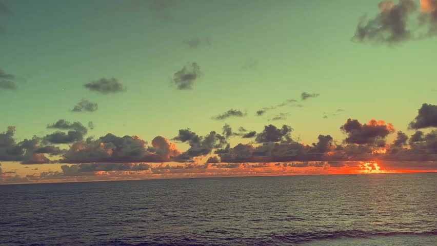 Sunset view over the ocean with clouds under a colorful sky
