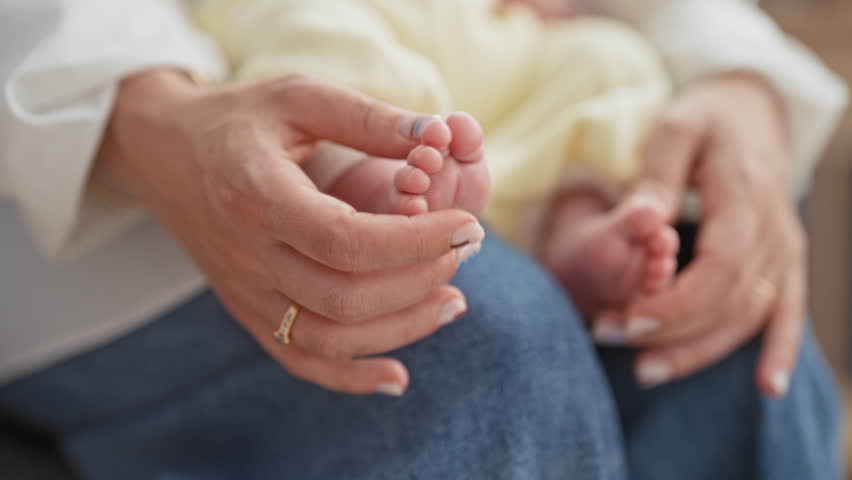 Newborn baby feet gently cradled by woman