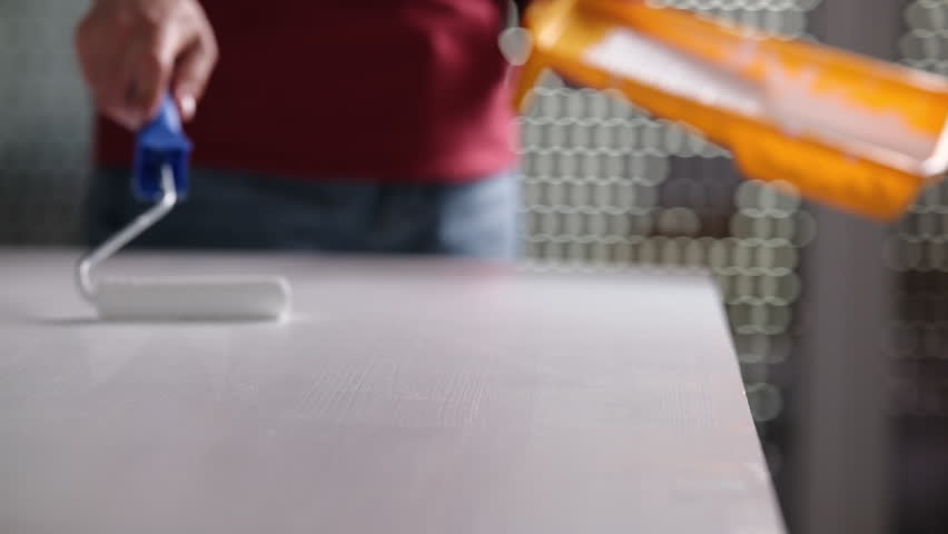 Girl Using A Roller And Brush To Paint A Wooden Board With White Paint