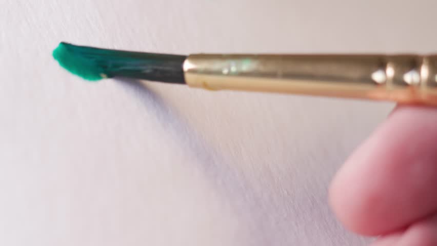 Close up of green watercolour drawing paints on paper. Artist draws with a brush, liquid analog effects for background with copy space for text in center. 