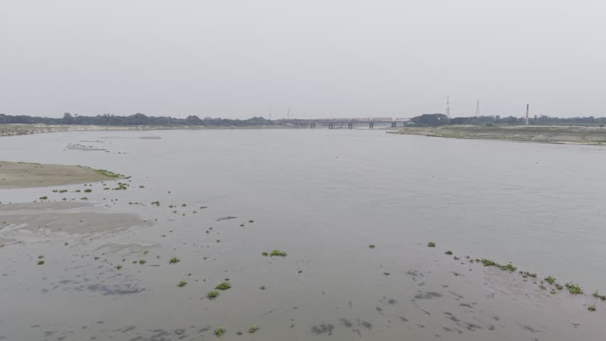 Aerial view of an eroded sandy shoreline with a bridge visible in the distance near the Garai River.
Description 3
