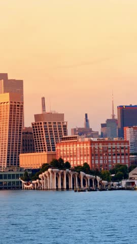 Little Island elevated park at sunset from the Hudson River, Manhattan. Curved concrete columns supporting greenery with warm toned towers behind.