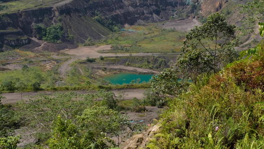 Looking into Panguna copper and gold mine pit with turquoise lake of water in Autonomous Region of Bougainville, Papua New Guinea