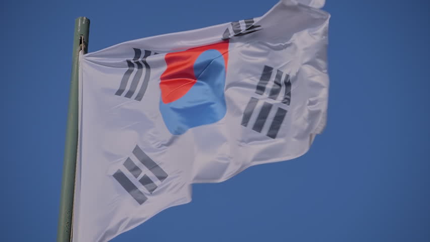Taegeukgi - the national flag of South Korea is fluttering in the wind against the clear blue sky - slow motion. Freedom, politics, patriotism, diplomacy and international affairs concept