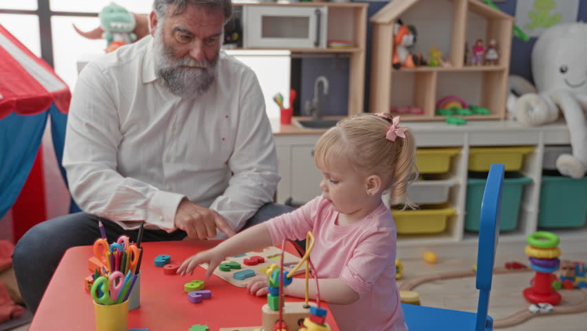 Man and little girl at a red table, girl handing a wooden shape block to the man