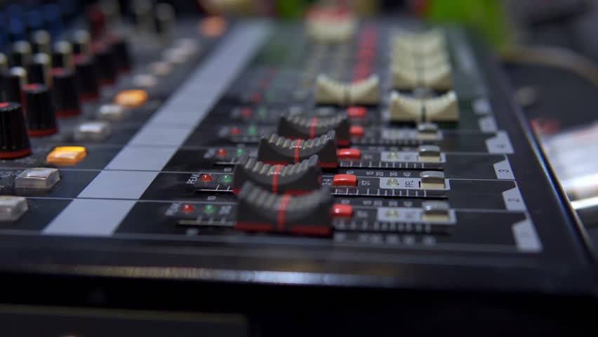 Close up of a sound mixer board with faders and buttons for television broadcasting
