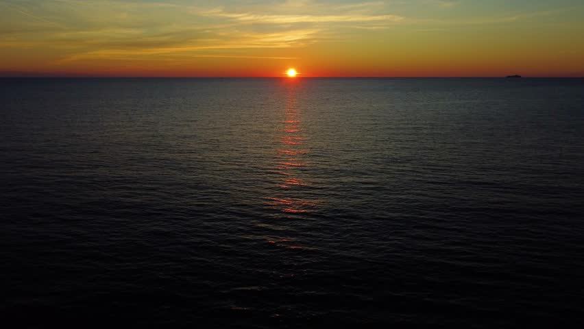 Stunning view of the sun setting over the calm adriatic sea horizon in dubrovnik, croatia. Golden light reflecting on the water surface