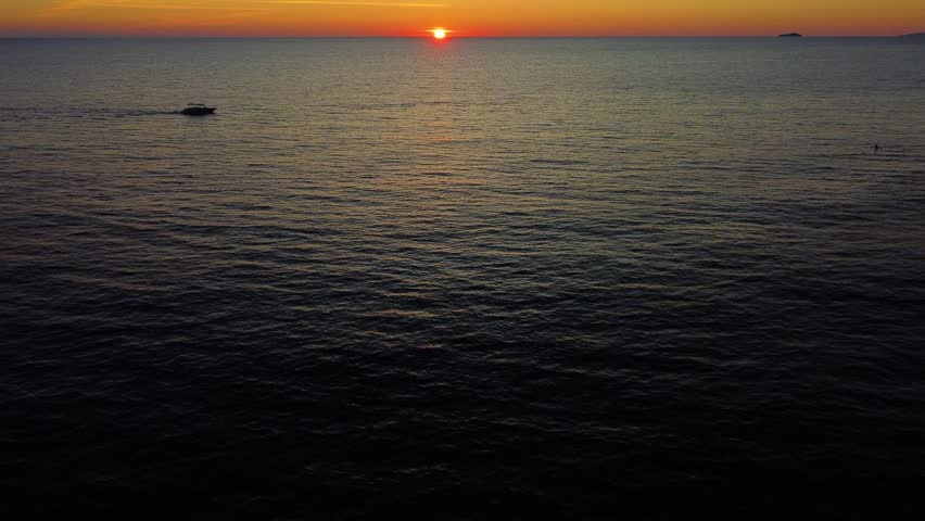 Golden sunset over the adriatic sea in dubrovnik, croatia. A speedboat calmly sails on the water, creating a serene and picturesque view