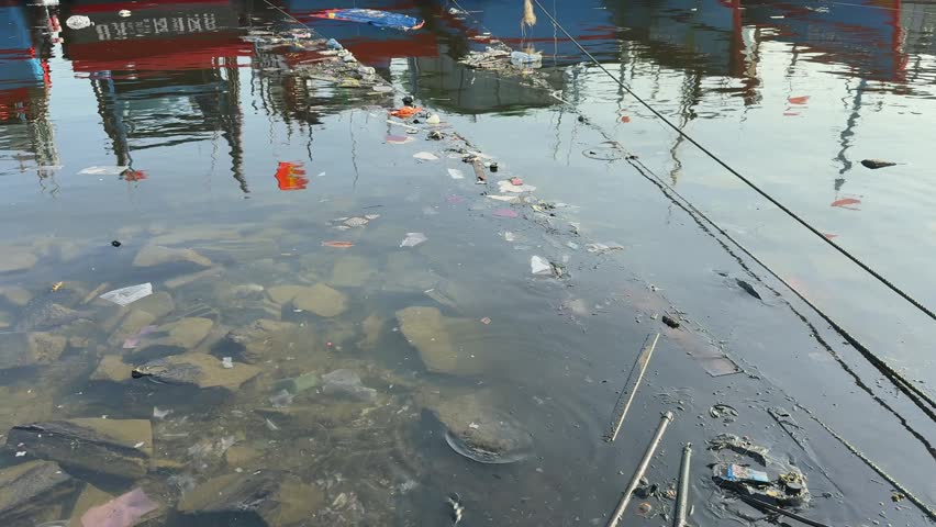Polluted Harbor Water with Floating Debris and plastic trash at Fishing Port