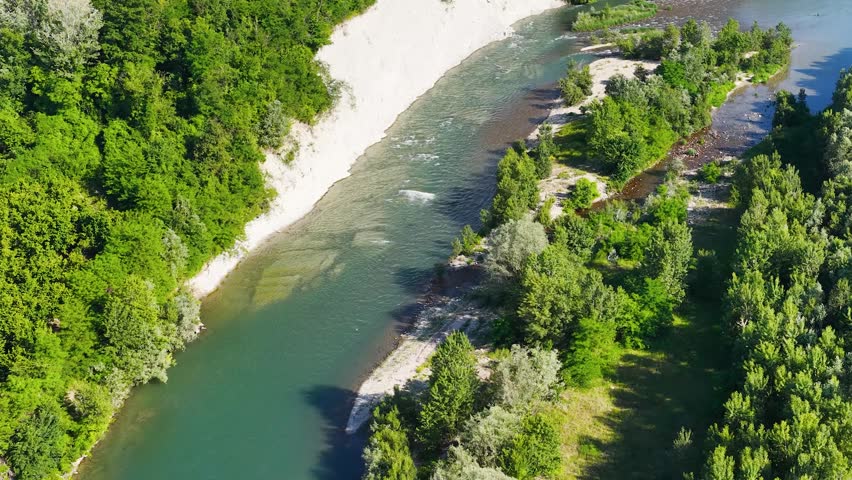 High-angle drone shot captures turquoise river water flowing past white cliffs and lush forests.