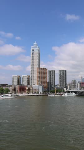 Aerial view of the modern skyline with skyscrapers and the Erasmusbrug bridge over the Nieuwe Maas river with boats on a sunny day, Rotterdam, Zuid-Holland, Netherlands.