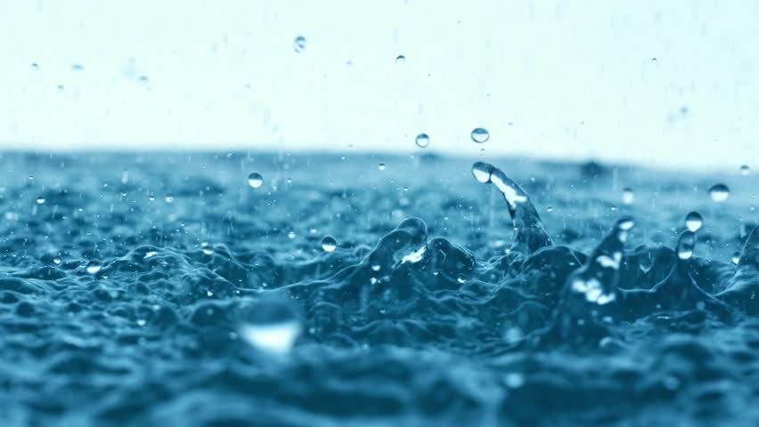 Raindrops falling on water surface, slow motion effect, ripples and splashes.