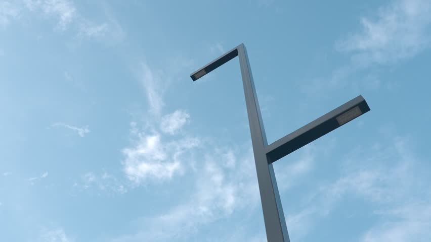 Modern streetlight rising against a bright blue sky with soft clouds and open copy space